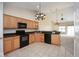 Kitchen featuring wood cabinetry, black appliances, tile floors, and view into living room at 6105 Franklin Villas Way, Indianapolis, IN 46237