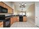 Kitchen featuring wood cabinets, black appliances, and tile flooring, open to the living room at 6105 Franklin Villas Way, Indianapolis, IN 46237