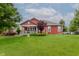 Backyard view of a beautiful home with a covered porch, manicured lawn, and mature trees at 6337 Ederline Ln, Noblesville, IN 46062