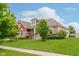 Charming home featuring a manicured lawn, stone accents, red siding, and lush landscaping at 6337 Ederline Ln, Noblesville, IN 46062