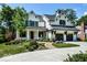 Charming two-story home featuring a black roof, white painted brick, and mature trees at 6450 Holliday E Dr, Indianapolis, IN 46260