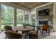Relaxing sunroom with fireplace and large windows offering views of the beautifully landscaped backyard at 6450 Holliday E Dr, Indianapolis, IN 46260