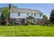 Expansive backyard with lush lawn, a wooden deck with outdoor seating, and manicured bushes and flowerbeds at 6649 Braemar S Ave, Noblesville, IN 46062