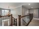 Well-lit staircase with wooden banister and chandelier leading to a second floor with neutral wall color at 6649 Braemar S Ave, Noblesville, IN 46062