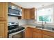 A kitchen showcases stainless steel appliances, wood cabinets, a double basin sink, and natural light through a window at 6838 Five Points Rd, Indianapolis, IN 46259
