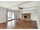 Spacious living room with dark wood floors, brick fireplace, and sliding glass doors to sunroom at 6838 Five Points Rd, Indianapolis, IN 46259