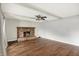 Living room featuring wood floors, a brick fireplace, neutral paint, and a ceiling fan at 6838 Five Points Rd, Indianapolis, IN 46259