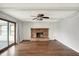 Bright living room featuring wood floors, brick fireplace, ceiling fan, and sliding glass doors at 6838 Five Points Rd, Indianapolis, IN 46259