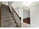 Carpeted stairs with wood railing leading to the upper level of the home at 6838 Five Points Rd, Indianapolis, IN 46259