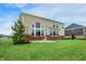 Exterior shot showcasing a tan two-story home with brick foundation, large windows and expansive green backyard at 7046 Allegiance Ct, Indianapolis, IN 46259