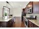 A kitchen with stainless steel appliances, granite countertops, dark wood cabinets, and views of the living room at 7046 Allegiance Ct, Indianapolis, IN 46259