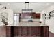 A kitchen featuring dark wood cabinets, stainless steel appliances, granite countertops and an island with a sink and modern lighting at 7046 Allegiance Ct, Indianapolis, IN 46259