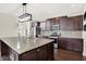 A kitchen featuring dark wood cabinets, stainless steel appliances, granite countertops and an island with a sink and modern lighting at 7046 Allegiance Ct, Indianapolis, IN 46259