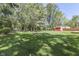 Spacious backyard with lush green grass, mature trees, fire pit, swing set, and a charming red shed at 8246 S Franklin Rd, Indianapolis, IN 46259