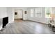 Bright living room featuring gray laminate flooring, white walls, and natural light from three large windows at 9002 Walton St, Indianapolis, IN 46231