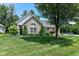 Beautiful brick home with manicured lawn and decorative shrubbery is shaded by mature tree at 11692 Seven Oaks Dr, Fishers, IN 46038