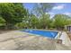 Backyard includes an in-ground pool that is lined with concrete and trees in the background at 1311 N Eaton Ave, Indianapolis, IN 46219