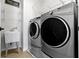 Modern laundry room equipped with new front load washer and dryer appliances, sink, and shelving at 13485 Mancroft Dr, Fishers, IN 46037