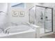 Bathroom featuring a soaking tub and glass enclosed shower with marble tile surround at 14458 Carlow Run, Carmel, IN 46074