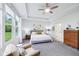 Bright bedroom with large windows and a chair features a modern ceiling fan and artwork at 14458 Carlow Run, Carmel, IN 46074
