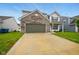 View of the home's two car garage and driveway with a manicured front lawn during daylight at 1454 Silver Pine Ln, Sheridan, IN 46069