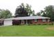 Charming brick home with attached garage, complemented by a lush green lawn and colorful landscaping at 1733 E 47Th St, Anderson, IN 46013