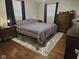 Comfortable bedroom featuring wood floors, a striped comforter, a nightstand, and dark blue curtains at 1733 E 47Th St, Anderson, IN 46013