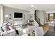 Cozy living room with an open floor plan, hardwood floors, large windows, and views of the kitchen and dining areas at 17721 Remy Rd, Noblesville, IN 46062