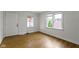 Bright bedroom featuring a wood-look floor, two windows, and a white paneled door at 2046 N Tibbs Ave, Indianapolis, IN 46222