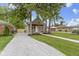 View of the charming home's front exterior, featuring a red porch, gravel driveway, and green lawn at 2046 N Tibbs Ave, Indianapolis, IN 46222