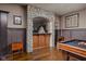 Basement bar featuring stone arch, wooden bar, billiard table, and wood paneled walls at 24 Shannon Rd, Zionsville, IN 46077