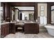 Luxurious bathroom vanity with dark wood cabinets, granite countertops and a large mirror at 24 Shannon Rd, Zionsville, IN 46077