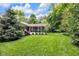 Picturesque backyard showcasing a screened porch, lush lawn, and mature evergreen trees at 445 W 63Rd St, Indianapolis, IN 46260
