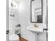 Modern bathroom with a pedestal sink, framed mirror, and a separate toilet area for added convenience at 445 W 63Rd St, Indianapolis, IN 46260