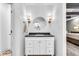 Stylish bathroom featuring white vanity with drawers, black countertop, round mirror, and sconce lighting at 445 W 63Rd St, Indianapolis, IN 46260