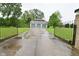 Gated driveway leads to a spacious three-car garage, surrounded by lush greenery and trees at 5135 Moller Rd, Indianapolis, IN 46254