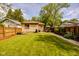Spacious backyard with a well-manicured lawn, wood fence, stone patio, and mature trees at 517 Bernard Ave, Indianapolis, IN 46208