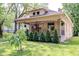 Charming single-Gathering home featuring a well-maintained lawn, lovely garden, and inviting covered porch with beautiful hanging plants at 517 Bernard Ave, Indianapolis, IN 46208
