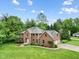 Aerial view of a well-maintained brick home, showcasing the roof, lawn, and surrounding trees at 5313 Redbird Dr, Columbus, IN 47201