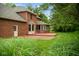 Backyard of brick home featuring a red deck, brick patio, and lush green lawn with mature trees at 5313 Redbird Dr, Columbus, IN 47201