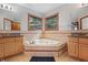 Bathroom featuring double sinks, tile floors, vanity, a corner tub and two windows at 5313 Redbird Dr, Columbus, IN 47201