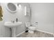 Clean bathroom features a pedestal sink, oval mirror, and modern toilet and storage shelf at 5313 Redbird Dr, Columbus, IN 47201