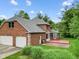 Back exterior showcasing brick house, well-maintained lawn, deck, and mature trees at 5313 Redbird Dr, Columbus, IN 47201