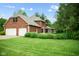 Rear view of brick home showcasing a well-manicured lawn, attached garage, and lush landscaping at 5313 Redbird Dr, Columbus, IN 47201