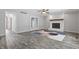 Living room with gray wood floors, painted fireplace, ceiling fan, and glass panel doors at 5313 Redbird Dr, Columbus, IN 47201