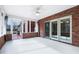 Spacious sunroom with brick walls, light tile flooring, and sliding glass doors leading to the outdoors at 5313 Redbird Dr, Columbus, IN 47201