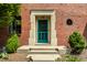 Close-up of brick home's entrance, showcasing a teal door and manicured greenery at 5401 N New Jersey St, Indianapolis, IN 46220