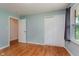 Comfortable bedroom with hardwood floors, closet, window, and soft blue walls at 6030 Riverview Dr, Indianapolis, IN 46208
