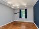 An inviting bedroom showcases hardwood floors, track lighting, and a bright window with dark curtains at 6030 Riverview Dr, Indianapolis, IN 46208