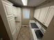 Bright laundry room featuring white cabinets, tan countertops, flooring, and modern appliances at 6609 N Tuxedo Ln, Indianapolis, IN 46220
